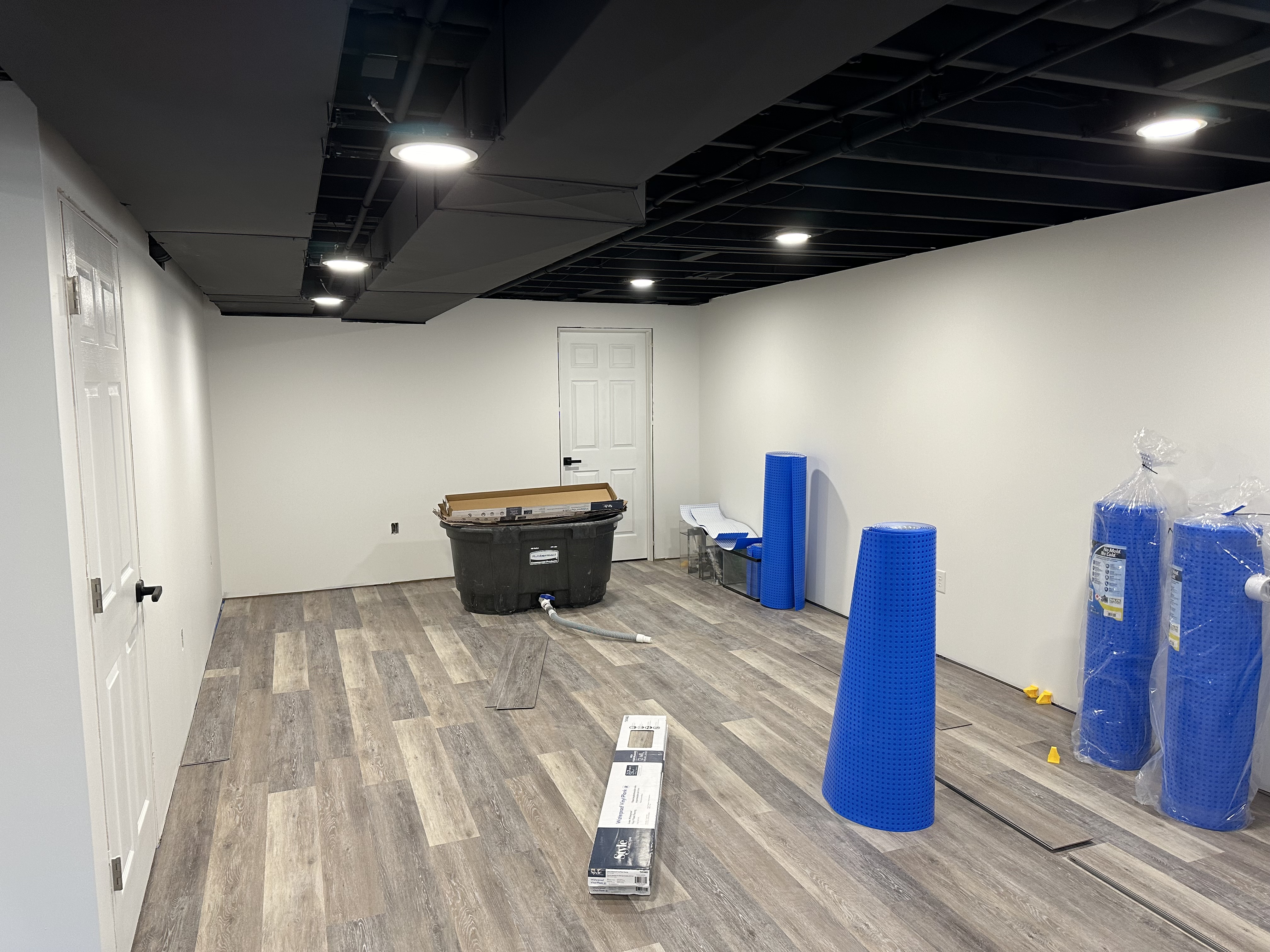Basement Remodel - Finished Basement with a black painted ceiling, recessed lighting, and new flooring. JB Painting Services did the drywall, paint, doors, and trim work for this basement in 4 days.
